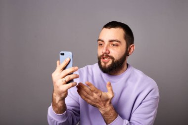 Akıllı telefonu elinde tutan adam video görüşmesi yapıyor. Çevrimiçi iletişim. Video kaydı ya da yaşam çevirisi