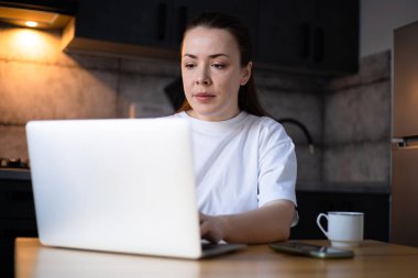 Work on the kitchen office. Remote work from home office. Young woman using laptop. Freelancer workplace at kitchen table. Distance education