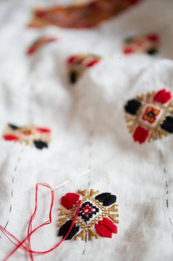 Beyaz kumaş üzerinde karmaşık kırmızı, siyah ve altın desenli el yapımı nakışların ayrıntıları. Geleneksel Ukrayna nakışı