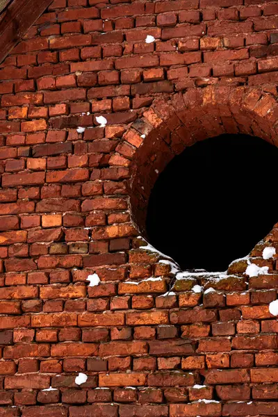 stock image Red Brick Wall With A Circular Window Under A Snowy Tree