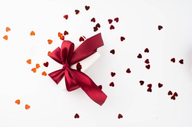White gift box with red bow on white background with red hearts. Holiday banner. Top view. Happy Valentines Day
