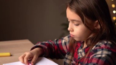 Genç kız, öğleden sonra sıcak bir odada, bir masada ev ödevleriyle boğuşuyor.