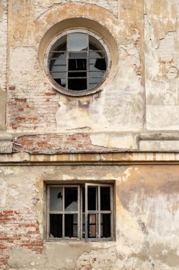 Kırık camlar ve doğal ışık altında kentsel bir ortamda boya soyan eski bir bina cephesi. Tarihi kilise Krakovets, Ukrayna