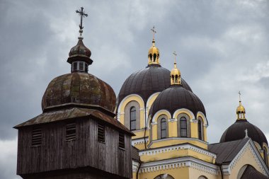 Modern kiliseye karşı altın kubbeleri olan tarihi ahşap kilise. Yavoriv, Ukrayna