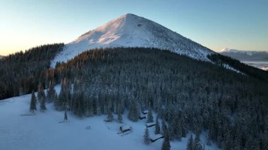 Karla kaplı dağ zirvesi gün batımında çevresindeki manzaranın nefes kesici manzarasını sunar. Kış boyunca Gorgany poligonu. Karpat Dağları, Ukrayna