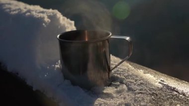 Kahve fincanı kış mevsiminde güneşin doğuşunda karlı çıkıntıda dinleniyor. Ukrayna 'nın Karpat Dağlarında Kış Yürüyüşü