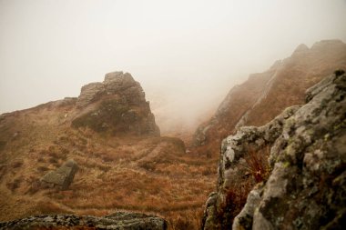 Sis, sonbaharda sakin bir günde uzak bir dağ manzarasında kayalık araziyi kaplar. Karpat Dağları, Ukrayna 'da sonbahar yürüyüşü