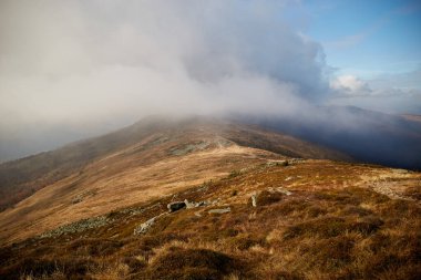 Öğleden sonra bulutları ve uzak tepeleri gösteren bir dağ sırtından manzara. Karpat Dağları, Ukrayna 'da sonbahar yürüyüşü
