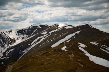 Bahar öğleden sonrası boyunca mavi gökyüzünün altında yeşil yamaçlı karla kaplı dağlar. Borzhava çiftliği. Karpat Dağları, Ukrayna