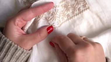 Uzman eller, bir krem kumaş üzerinde ince işlemeler yapar ve bir el işi sırasında detaylara çok özen gösterir. Geleneksel Ukrayna Nakışı