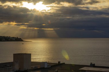 Akdeniz kıyısında gün doğumu, Alicante. Güneş ışınları bulutları delip geçer. Ön plandaki evlerin çatıları. Yüksek kalite fotoğraf