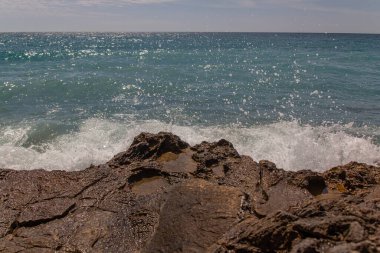 Akdeniz manzarasının ön planında güzel granit taşlar. Dalgalar, su sıçramaları. Güneşli bir gün. Yüksek kalite fotoğraf
