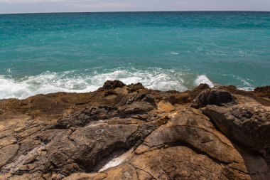 Akdeniz manzarasının ön planında güzel granit taşlar. Dalgalar, sıçramalar, suyun mavi rengi. Güneşli bir gün. Yüksek kalite fotoğraf