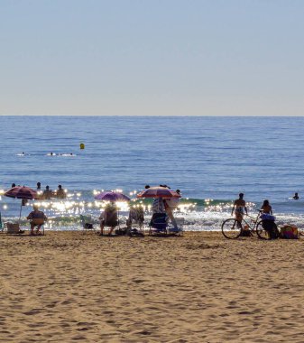 İnsanlar arka planda deniz kenarında dinleniyor, uzaktan bakıyorlar, suda güneş parlıyor. Yüksek kalite fotoğraf