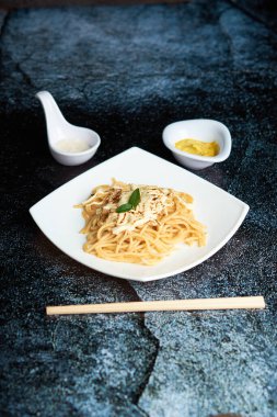 Küçük domatesli spagetti, yemek çubukları ve koyu arka plan kullanıyor.