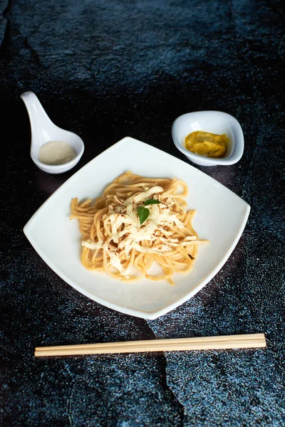 stock image spaghetti with little tomato, using chopsticks, dark background