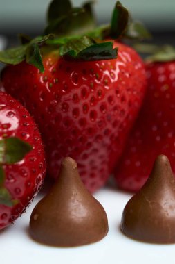 Önünde iki öpücük çikolatası olan çilekler.