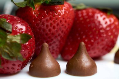 Önünde iki öpücük çikolatası olan çilekler.
