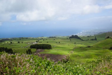 Portekiz, Azores 'in yeşil tepelerinin ve açık arazilerinin muazzam manzarası. Arka planda Atlantik Okyanusu var. Huzurlu ve doğal bir manzara..