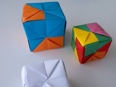 Asgari gölgeli beyaz bir yüzeye yerleştirilmiş parlak modüler origami küpleri.