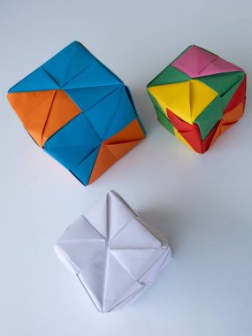 Asgari gölgeli beyaz bir yüzeye yerleştirilmiş parlak modüler origami küpleri.