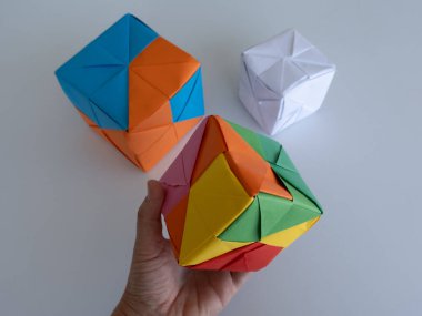 Asgari gölgeli beyaz bir yüzeye yerleştirilmiş parlak modüler origami küpleri.