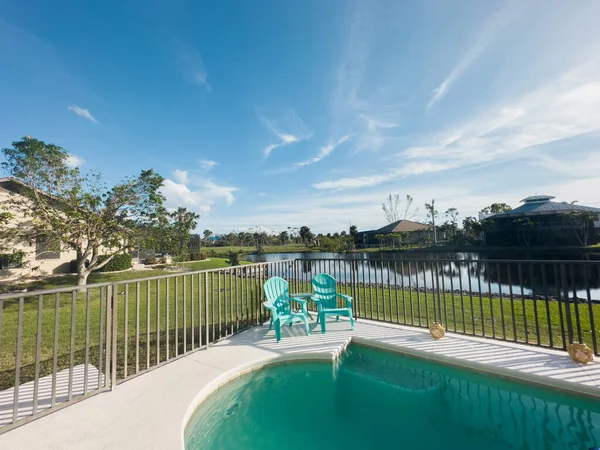 Florida home with back yard pool with blue skies. Rental property Florida. Lake surrounding