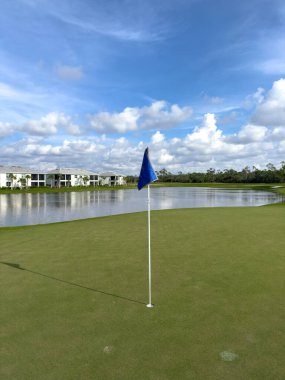 Golf sahası yeşil, delik ve bayrak mavi gökyüzü ve güneş. Bozulmamış, yemyeşil bir yer. Güneybatı Florida.