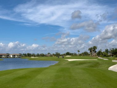 Mavi gökyüzü ve güneşli golf sahası. El değmemiş yemyeşil çimenlik çim ve su. Güneybatı Florida.
