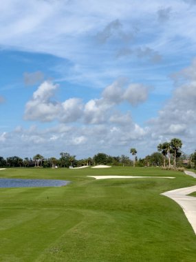 Mavi gökyüzü ve güneşli golf sahası. El değmemiş yemyeşil çimenlik çim ve su. Güneybatı Florida.
