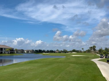 Mavi gökyüzü ve güneşli golf sahası. El değmemiş yemyeşil çimenlik çim ve su. Güneybatı Florida.