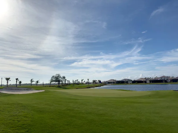 stock image Golf course with blue skies and sun. Pristine lush rich green fairway turf and water. Southwest Florida.