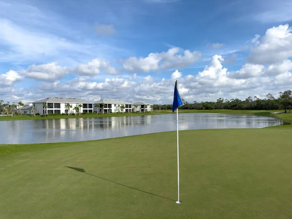 Golf sahası yeşil, delik ve bayrak mavi gökyüzü ve güneş. Bozulmamış, yemyeşil bir yer. Güneybatı Florida.