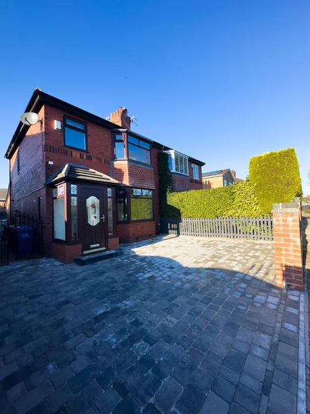 Semi detached house in Manchester, United Kingdom. Blue sky with block paved drive