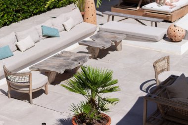Ahşap kanepe ve sehpa rahat modern terasta, güneşli bir otelde teras.