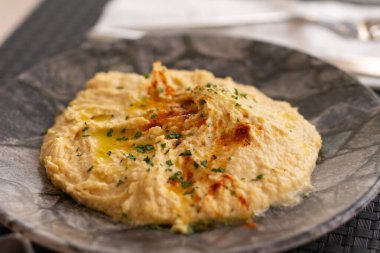 Humus. Restoranda kırmızı biber ve otlarla süslenmiş büyük bir kase humus.