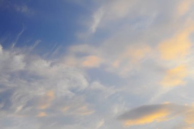 Akşam gökyüzünün arka planı, güneşte uzanan bulutlar. Gökyüzü, sıcaktan soğuğa doğru bir renk değişimiyle.