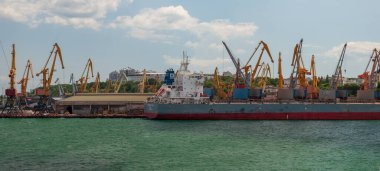 Odesa, Ukrayna. 22 Temmuz 2021. Yazın Karadeniz limanının panoraması. Turnalar bir ticaret gemisini boşaltır..