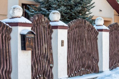 Tahtadan yapılmış orijinal çitler ve taşaklı taş sütunlar. Çiftliğin çitleri, posta kutusuyla.