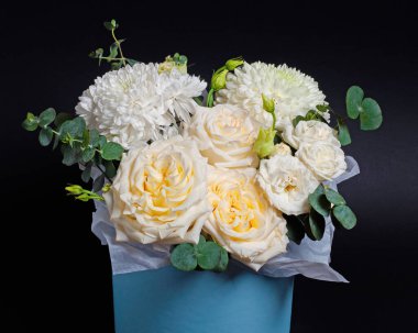 Bir buket beyaz gül ve okaliptüs filizli kasımpatı, koyu arkaplan.