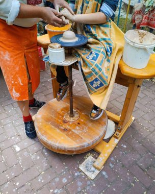 Çömlekçilik yüksek lisansı. Çömlek tezgahında kil çömlek yapma dersi. Gerçek, sahnelenmemiş sokak fotoğrafı.