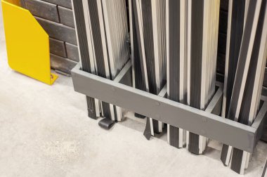 Beton zeminde düzgünce yerleştirilmiş kauçuk burunlu alüminyum merdiven ve koruma amaçlı sarı bir koruma..