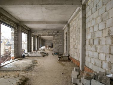 İnşaat halindeki beton duvarlarla çevrili bitmemiş bir binanın içerisi.