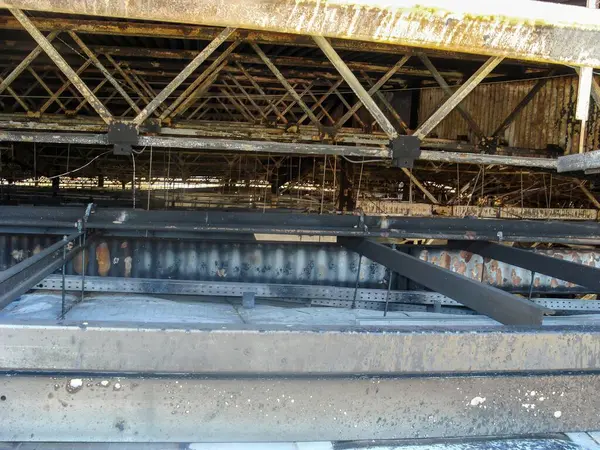 stock image Fire-damaged support structures in an industrial warehouse, with visible soot and rust.