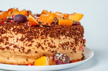 Mandalina, üzüm ve fındıkla süslenmiş çikolatalı kekin yakın çekimi..