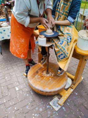 Kyiv, Ukrayna. 10 Aralık 2023. Çömlek atölyesi. Bir öğretmen ve bir öğrenci çömlek çarkında kil çömlek şekillendirir. Bir festivalden sokak fotoğrafı.