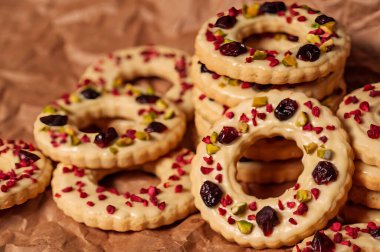 Beyaz jöleli, kızılcıklı ve yakın plan fıstıklı Noel kurabiyeleri. Geleneksel tatil kurabiyeleri şık dekorasyon sayesinde modern bir görünüme kavuşuyor..