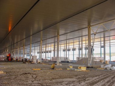 Çelik yapı ve tavan panelleri monte eden işçilere sahip modern inşaat alanı.