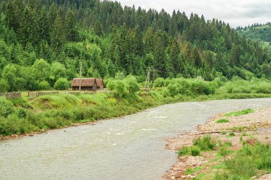Huzurlu bir nehir, yemyeşil bir vadi boyunca akar. Kıyısında güzel bir ahşap ev bulunur..
