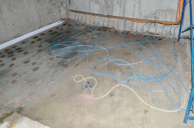 Beton bir odada, mavi borularla döşenmiş, beton döşenmiş, mavi borular döşenmiş, doldurulmaya hazır..